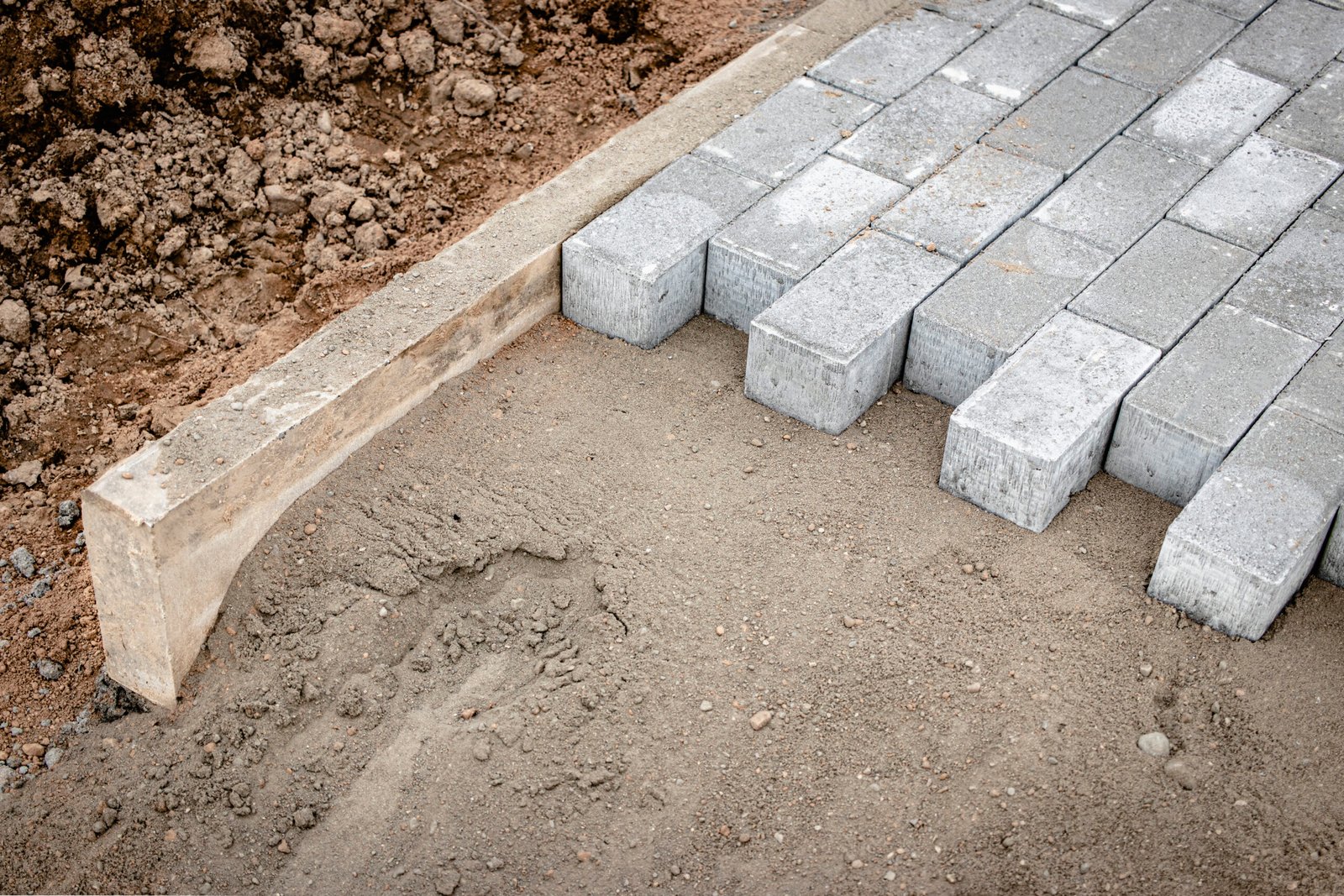 Pavement repair and laying of paving slabs on the walkway, stacked tile cubes on the background. Laying paving slabs in the pedestrian zone of the city, sand filling. Road tiles and curbs. Pavement repair and laying of paving slabs on the walkway, stacked tile cubes on the background. Laying paving slabs in the pedestrian zone of the city, sand filling. Road tiles and curbs