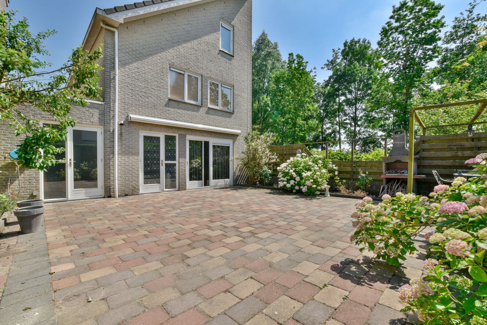 Amsterdam, Netherlands - 10 April, 2021: a brick patio with flowers and trees in the back yard on a sunny summer day, taken from above it